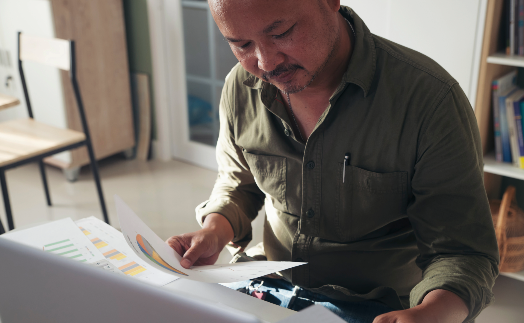 Man looking at documents with charts and graphs in a workspace.