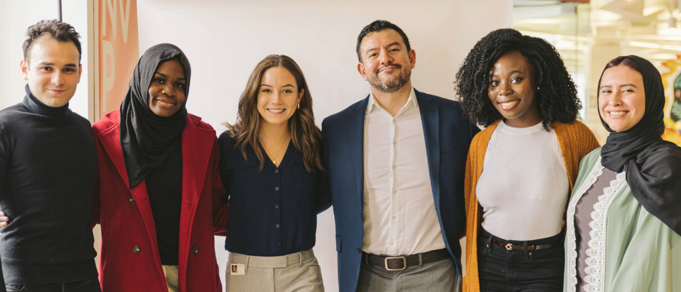 Group of seven diverse professionals smiling together in an office.