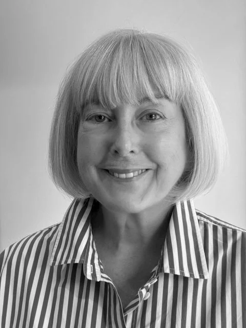 A woman with shoulder-length hair smiling, wearing a striped shirt.