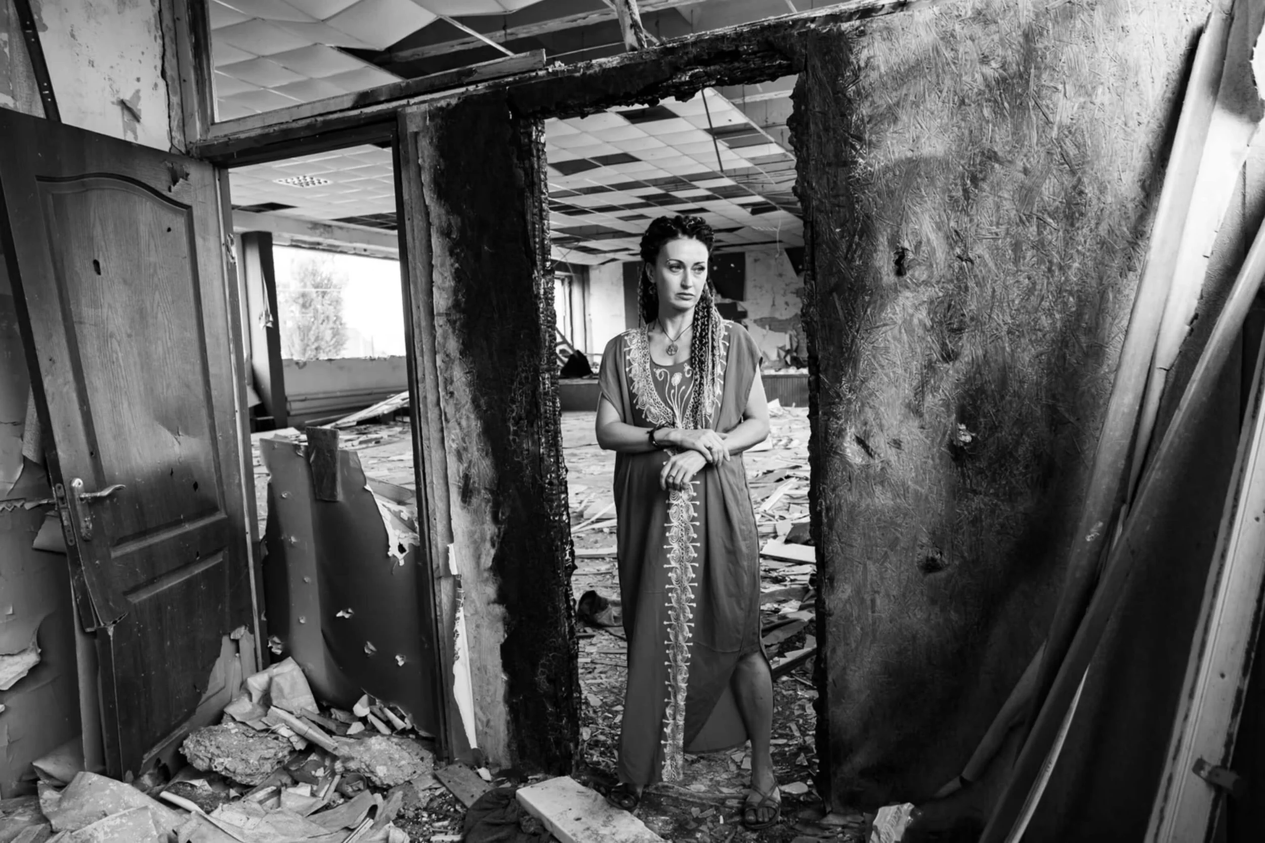 Image of a woman standing in a doorway of a destroyed room