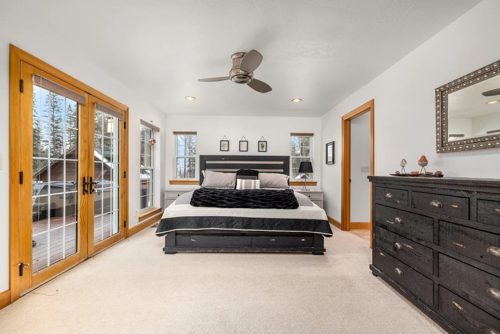 Bedroom with a bed, nightstands, dresser, large windows, and glass sliding doors leading to a deck.