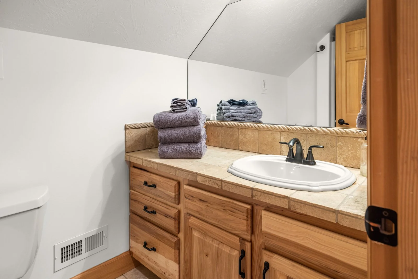 Bathroom vanity with stacked towels, a sink, and a large mirror.