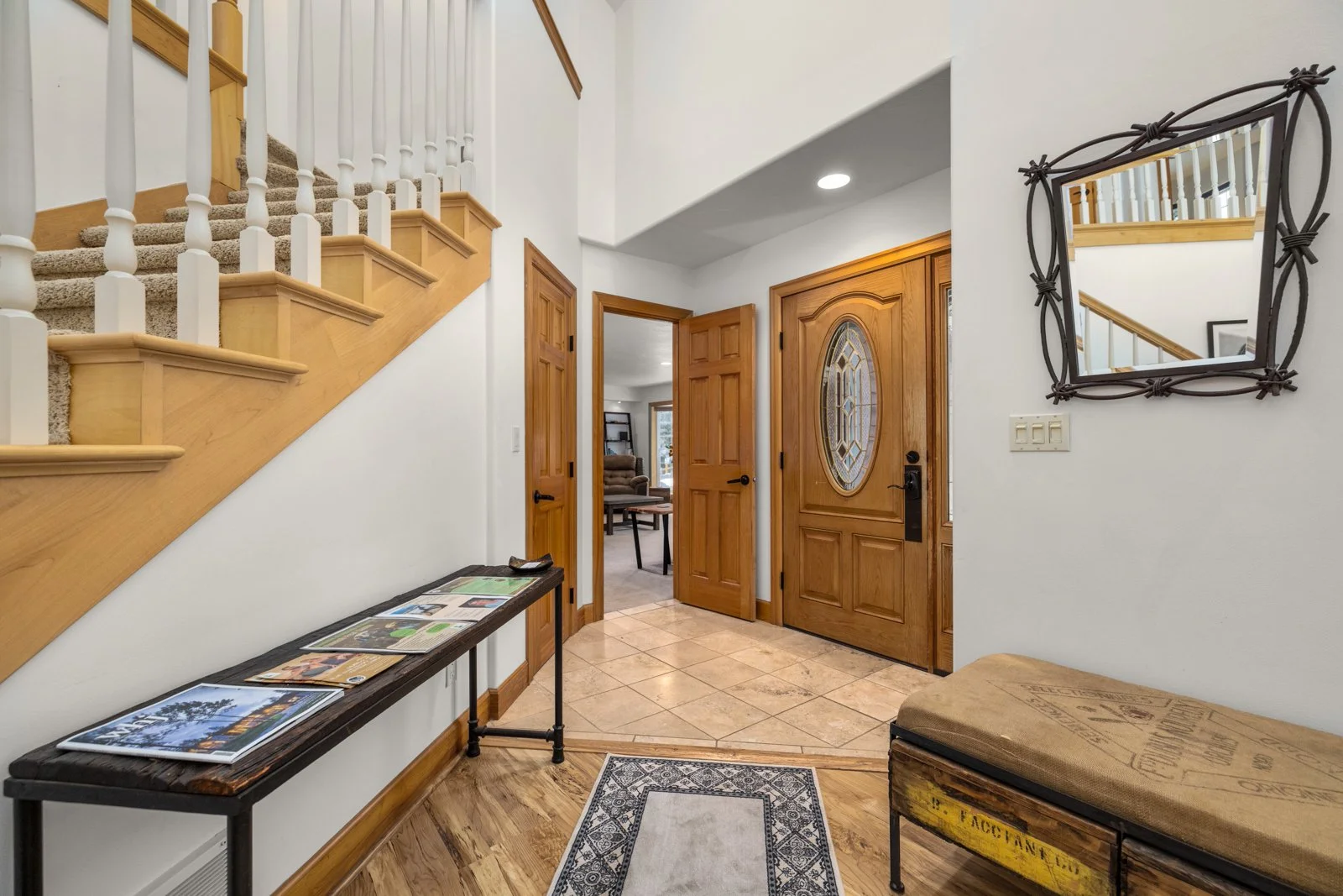 Entryway with wooden door, staircase, mirror, and hallway to a living space.