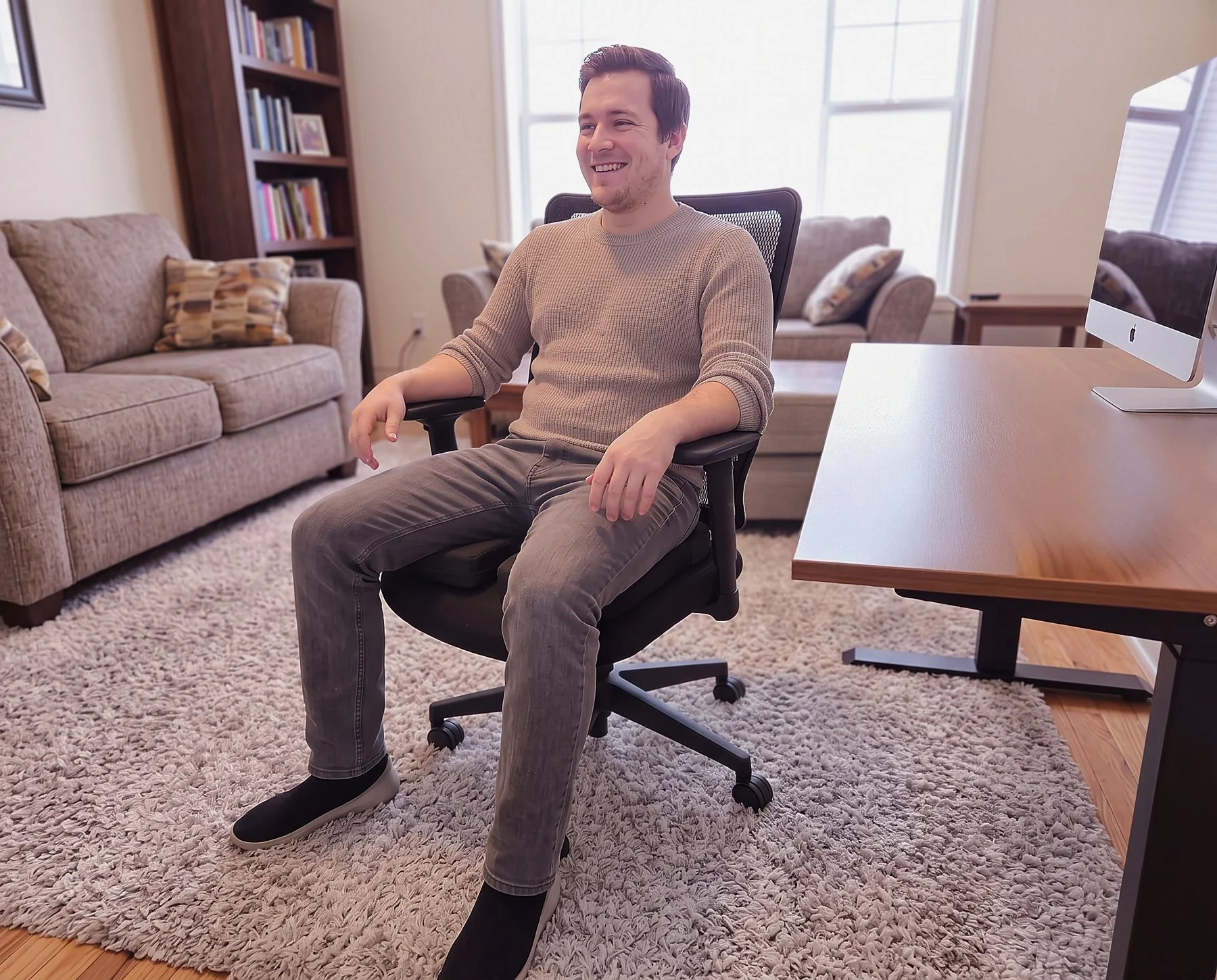 Man sitting relaxed and smiling on an office chair fitted with a Twin Cheeks two-panel seat cushion