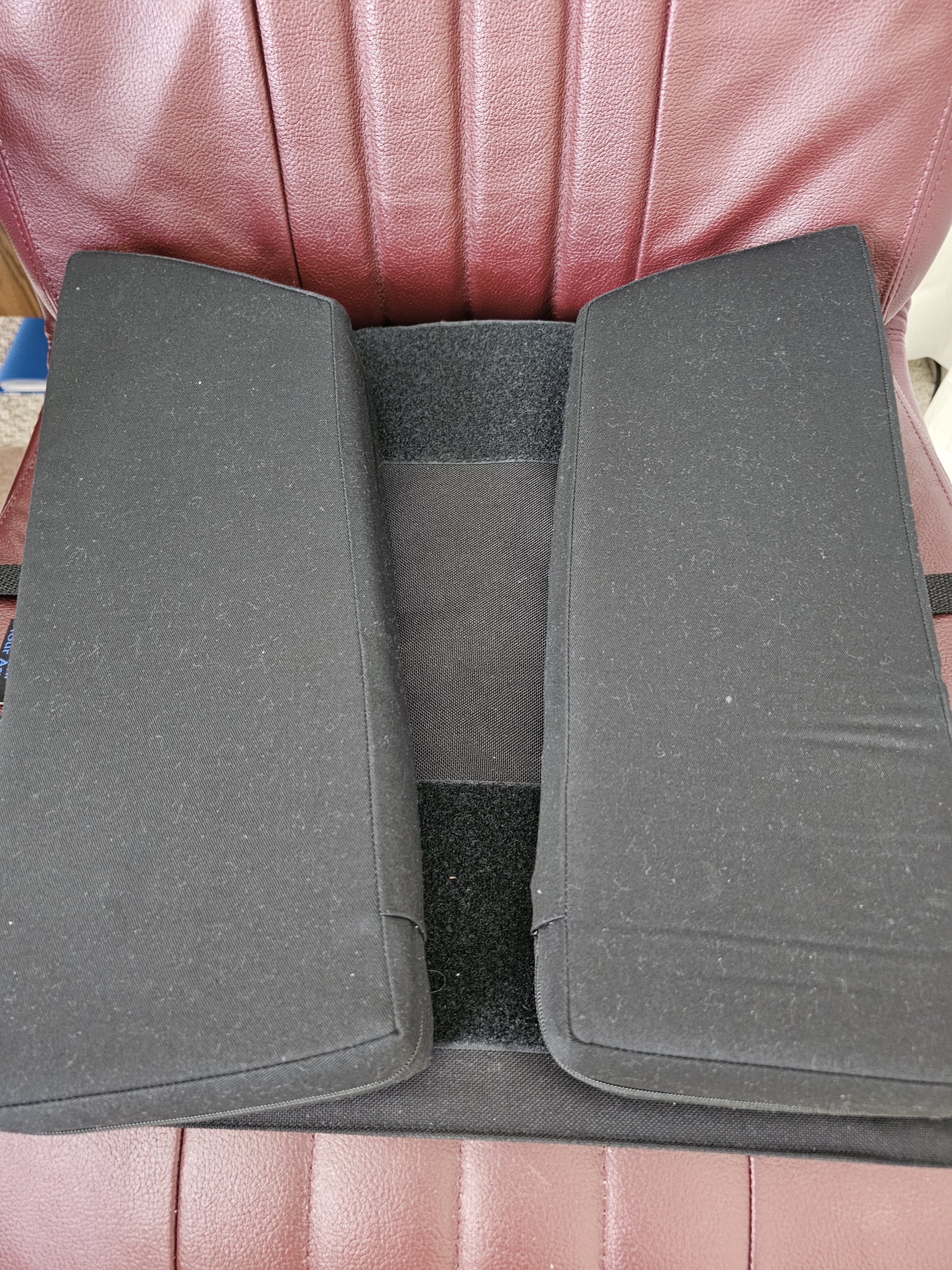 Twin Cheeks cushion turned around with its two panels spread wider apart on a leather chair