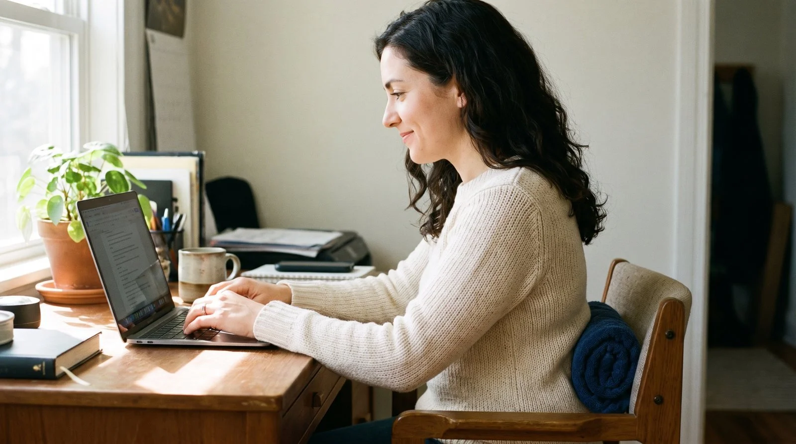 Woman sitting comfortably at her desk with a rolled towel behind her lower back to take weight off her sit bones