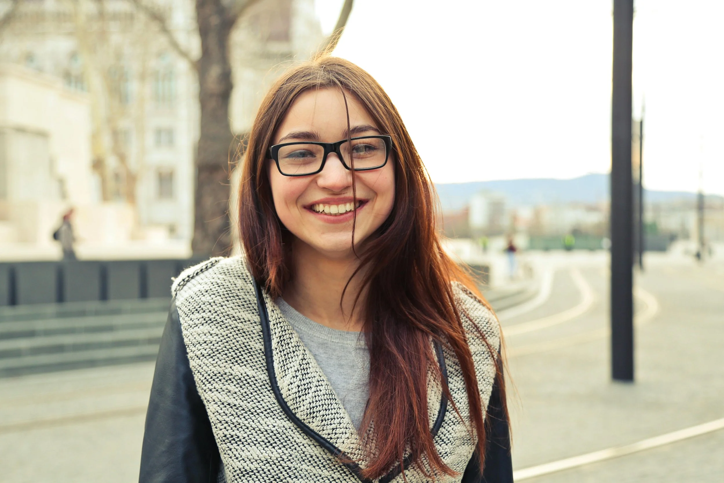 Adolescent girl smiling with brown hair and glasses