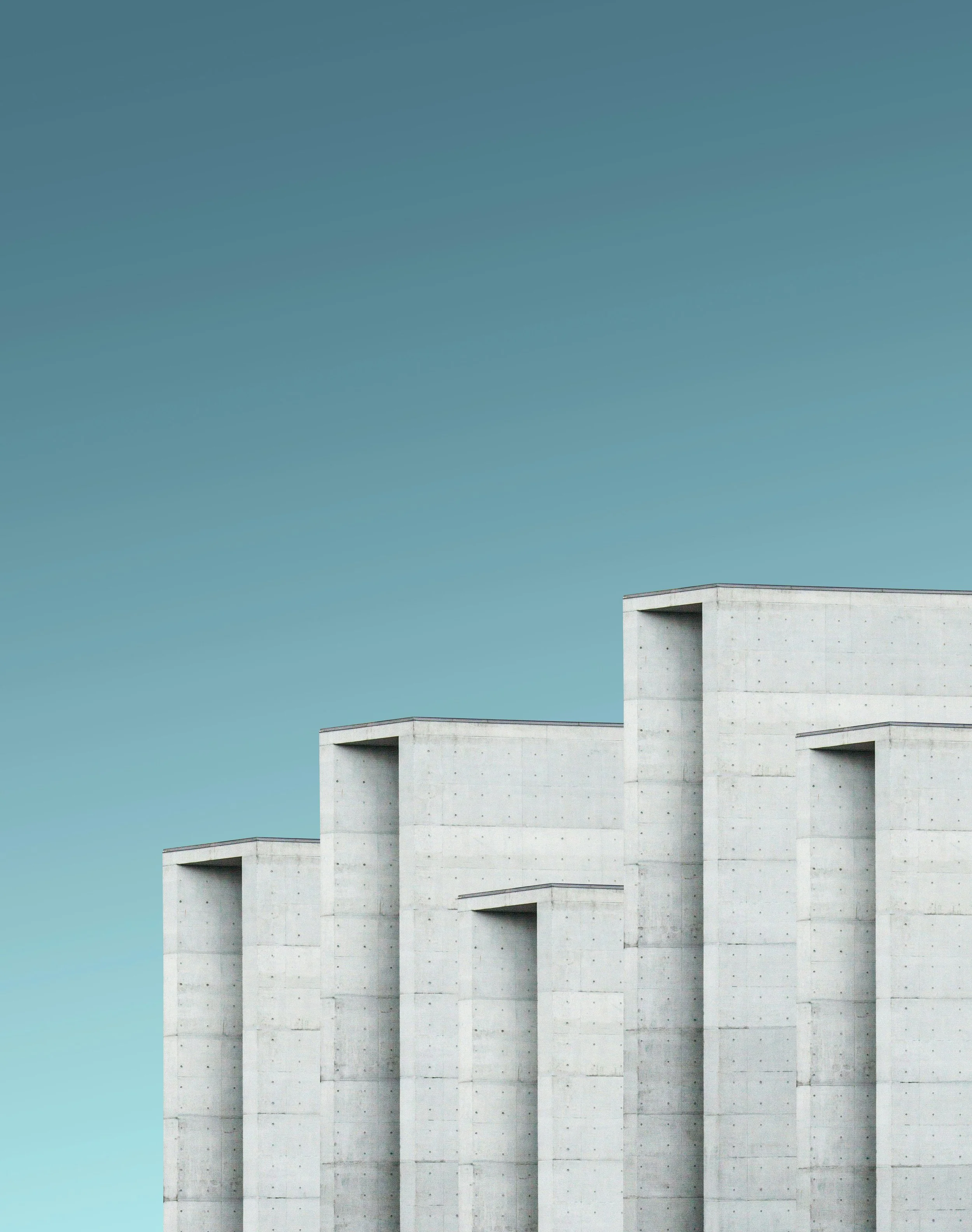 Modern concrete building with tall, rectangular structures against a clear blue sky.