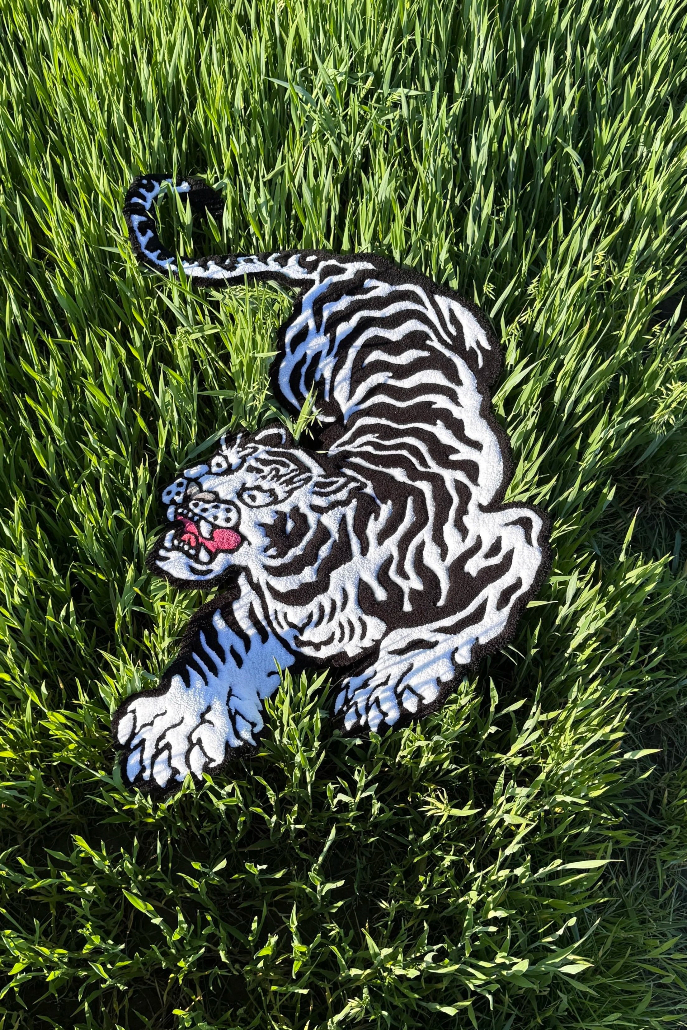Colorful tiger patch with black, white, and blue stripes on grass.