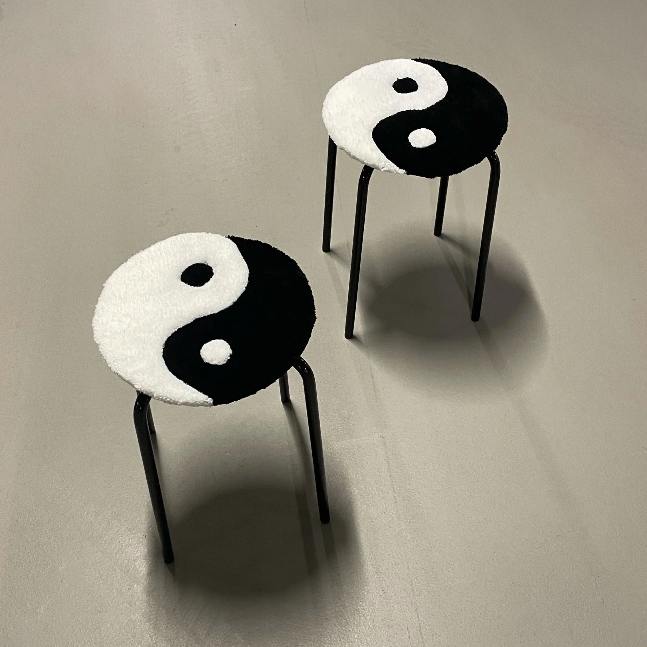 Two small chairs with yin-yang symbol cushions on the seats, placed on a plain gray floor.