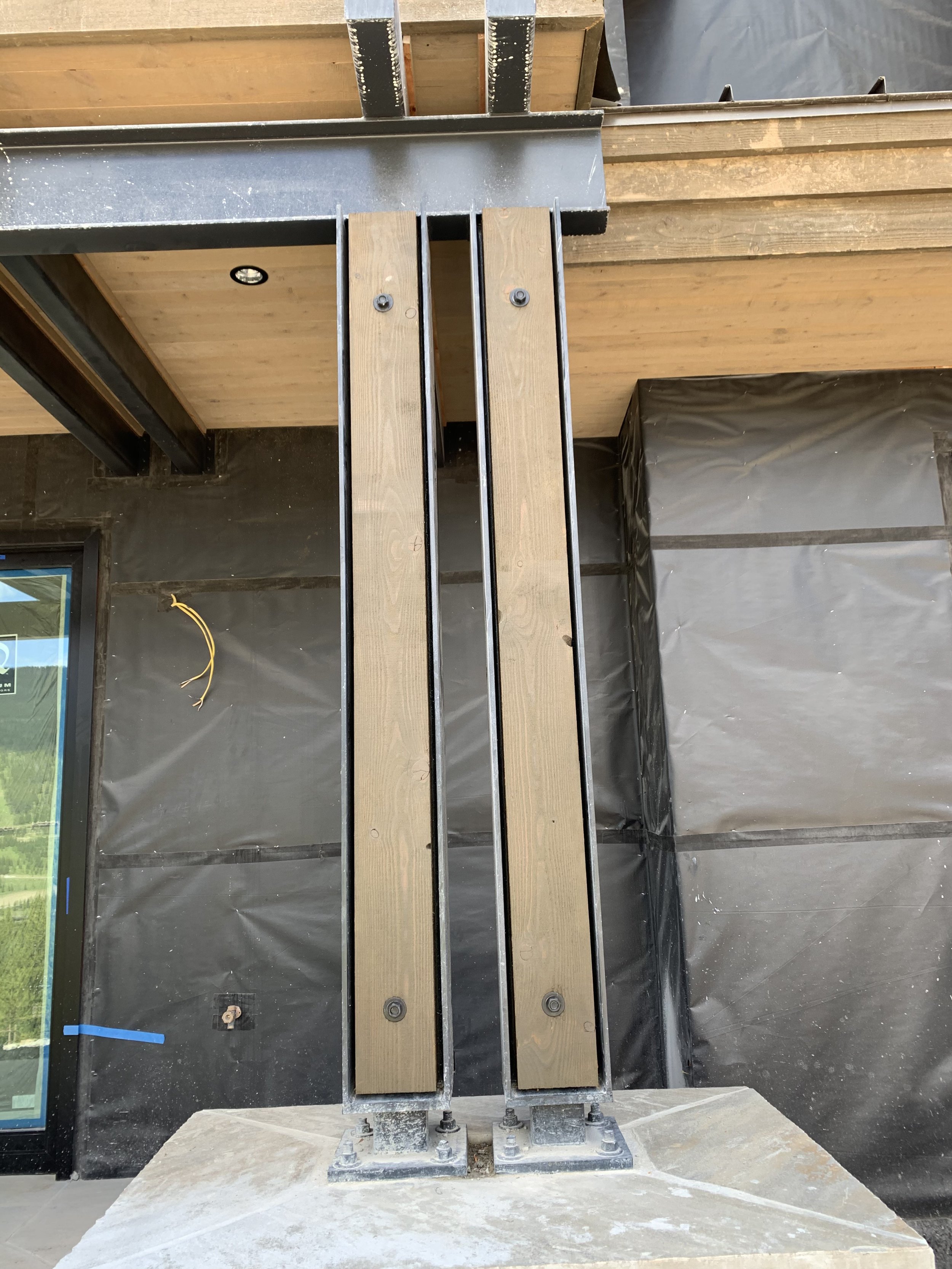Two parallel wooden benches on a metal structure outside a building under construction.