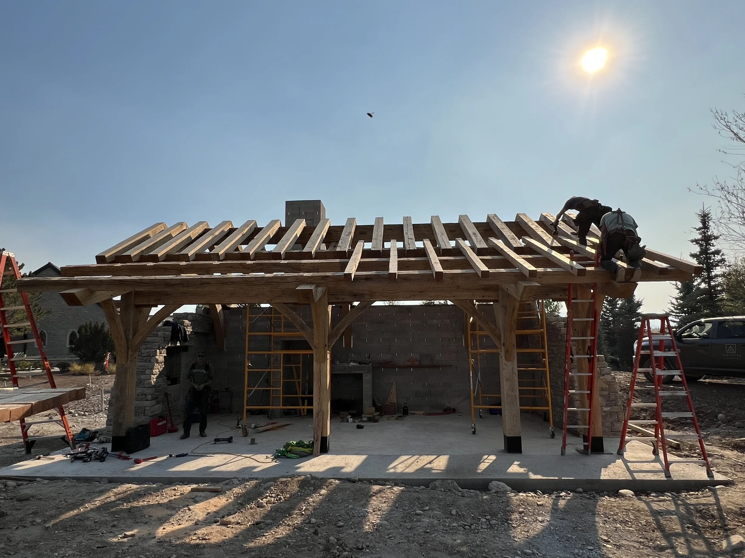 Construction workers building a wooden roof structure on a house during daytime.
