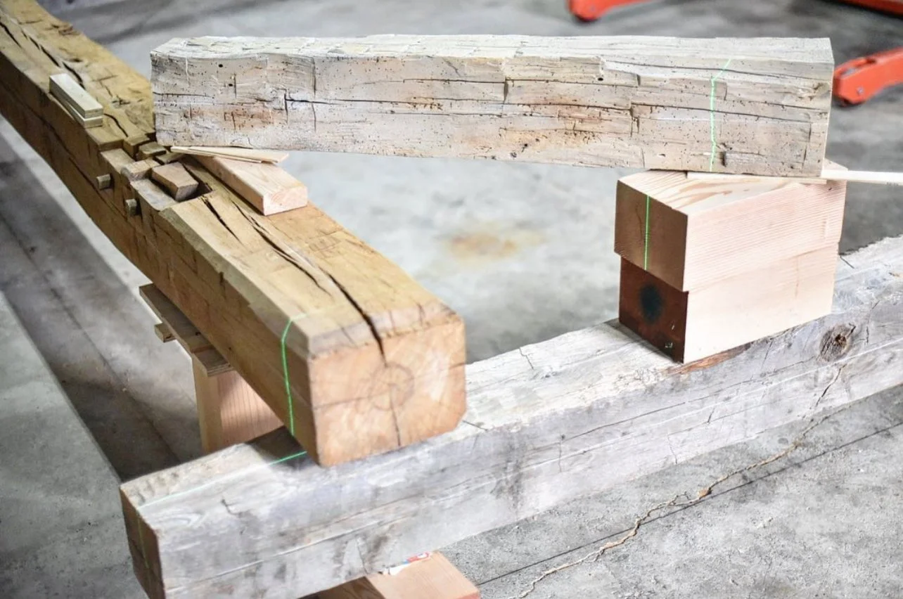 Various pieces of cut wood, including a large weathered plank, in a workshop or construction setting.