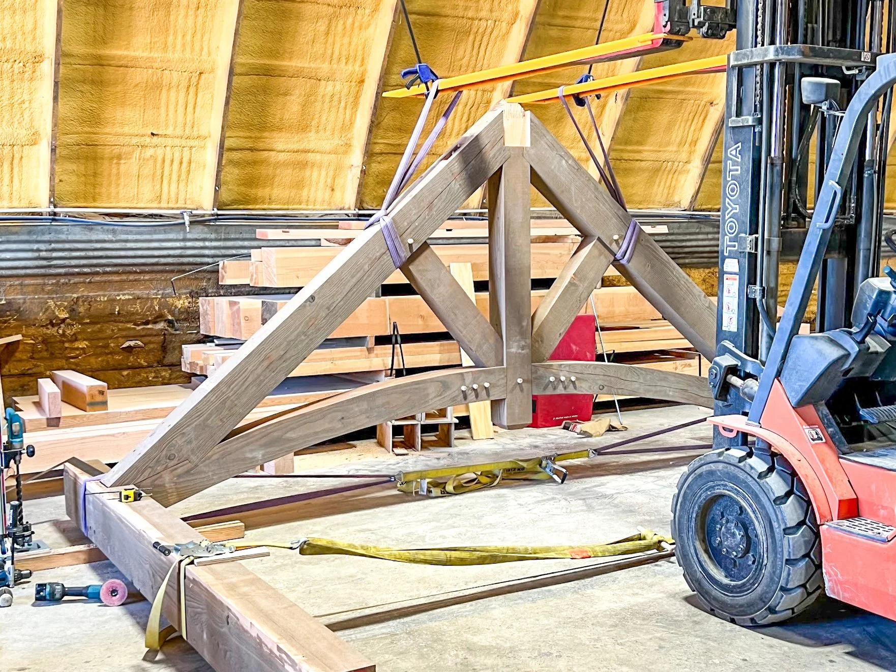 Construction site inside a building with wooden framing, a red forklift, and various lumber and tools.
