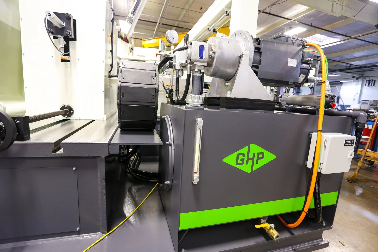 Industrial machine with the green GHP logo, various components, wires, and pipes in an industrial setting.