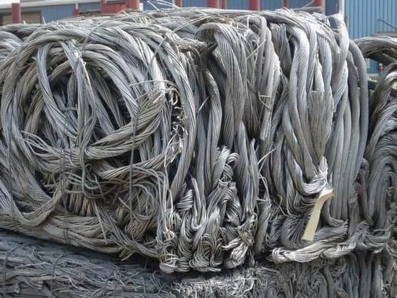 Coiled steel wire cables stacked on a surface outdoors with a blue building in the background.