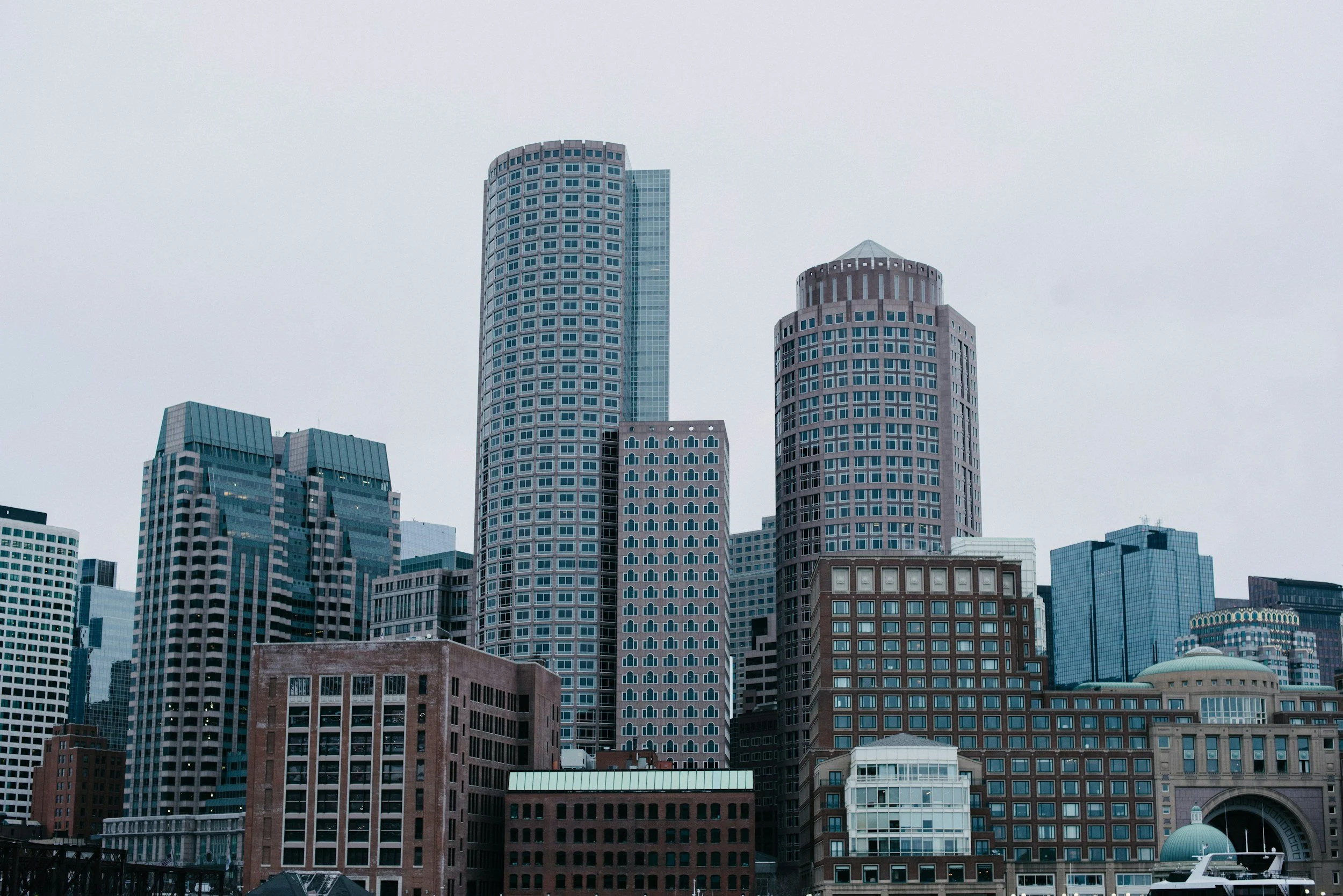 City skyline with tall modern skyscrapers under an overcast sky.