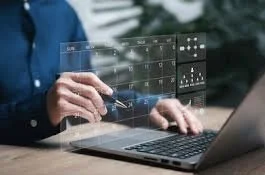 Person working with holographic digital interface on a laptop, analyzing data and graphs.