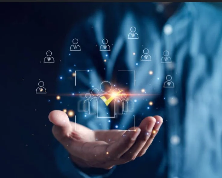 A person in a suit holding out their hand with a floating digital graphic of people icons and a checkmark, representing network selection or verification.