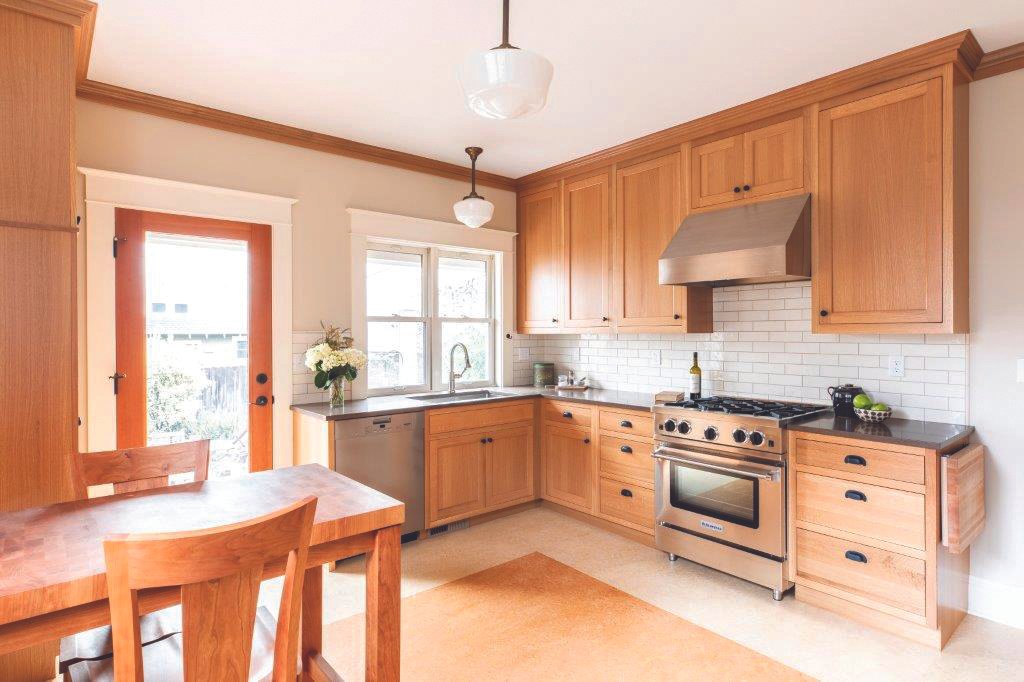 Kitchen with wooden cabinets, stainless steel appliances, white tile backsplash, and a wood dining table and chairs.