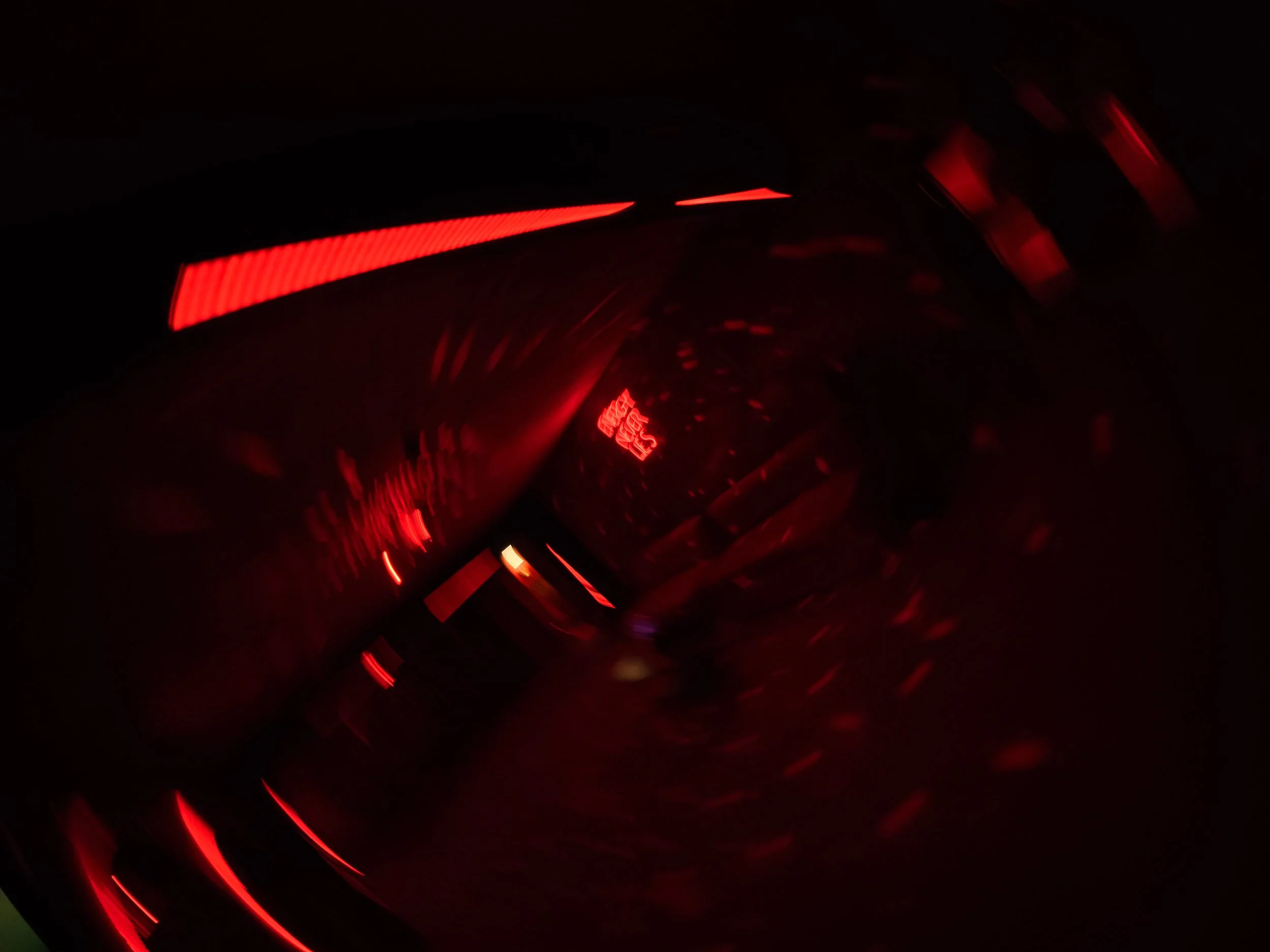 Imagen oscura con luces rojas y letras en medio, crea un efecto borroso y abstracto.