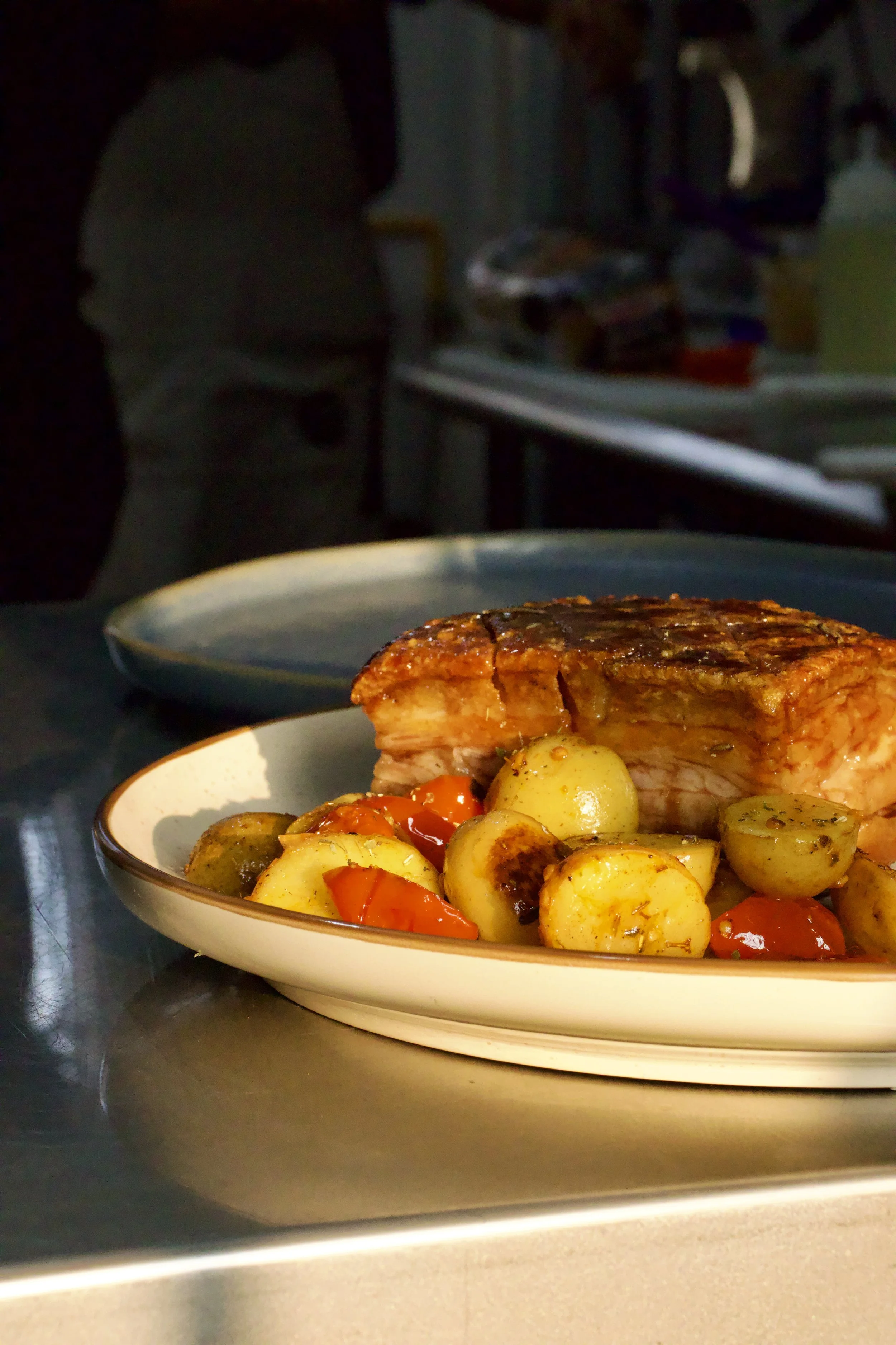 Plato con porción de carne acompañada de papas pequeñas y tomates cherry.