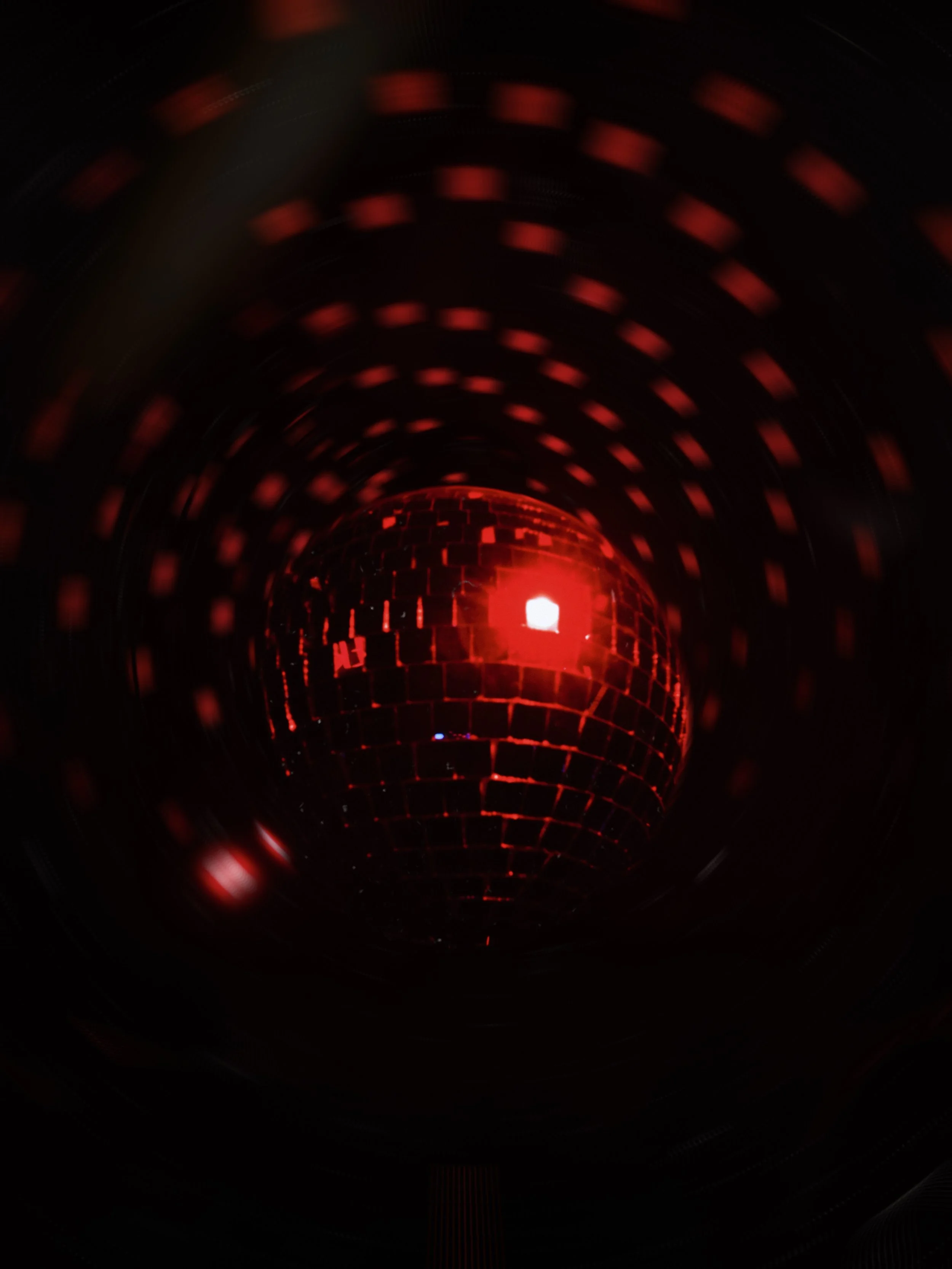 Esfera disco con reflejos brillantes en un entorno oscuro, con luces rojas y patrones de cuadrícula.