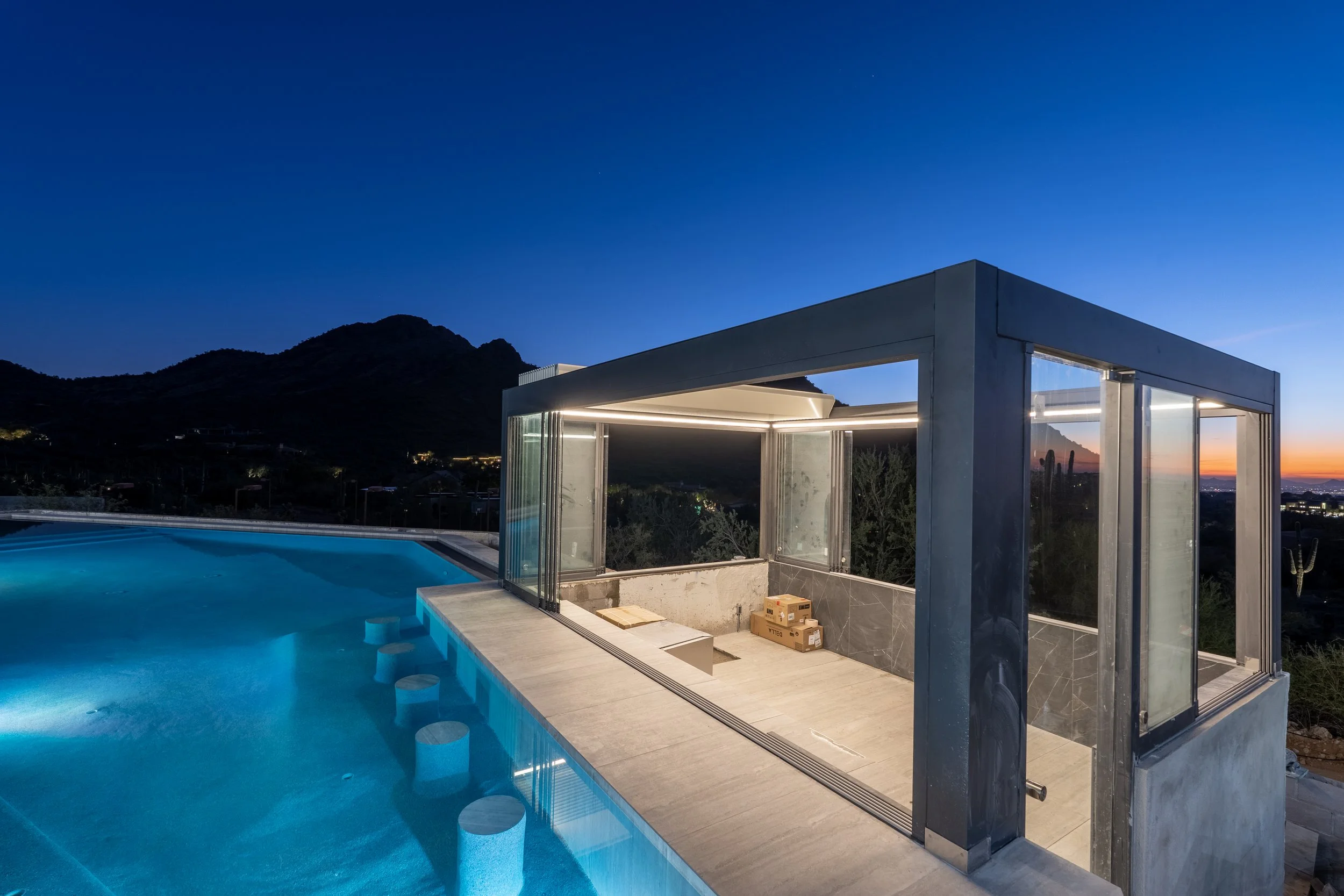 Cantilevered casita over pool with glass walls and integrated lighting.