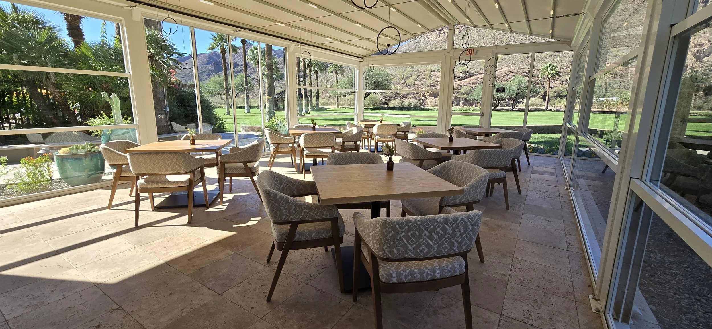 Seating area overlooking the main lawn; glass walls fully lowered for panoramic views of the mountain range.