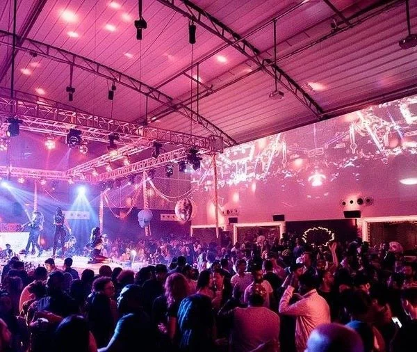 High-capacity retractable soft-top pavilion hosting a live performance with immersive lighting and production.
