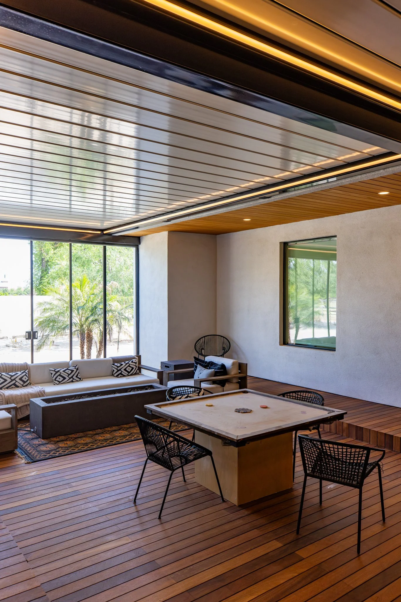 Retractable roof open above residential courtyard in Chandler showing seamless indoor-outdoor transition with lounge and fire table.