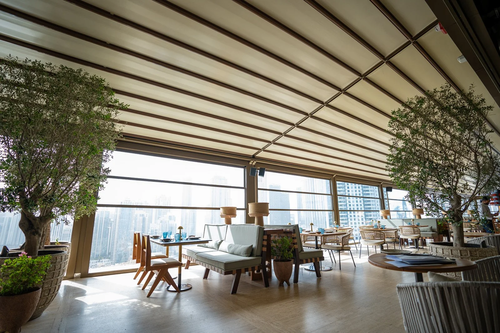 Contemporary rooftop restaurant with beige retractable fabric canopy and city skyline view.