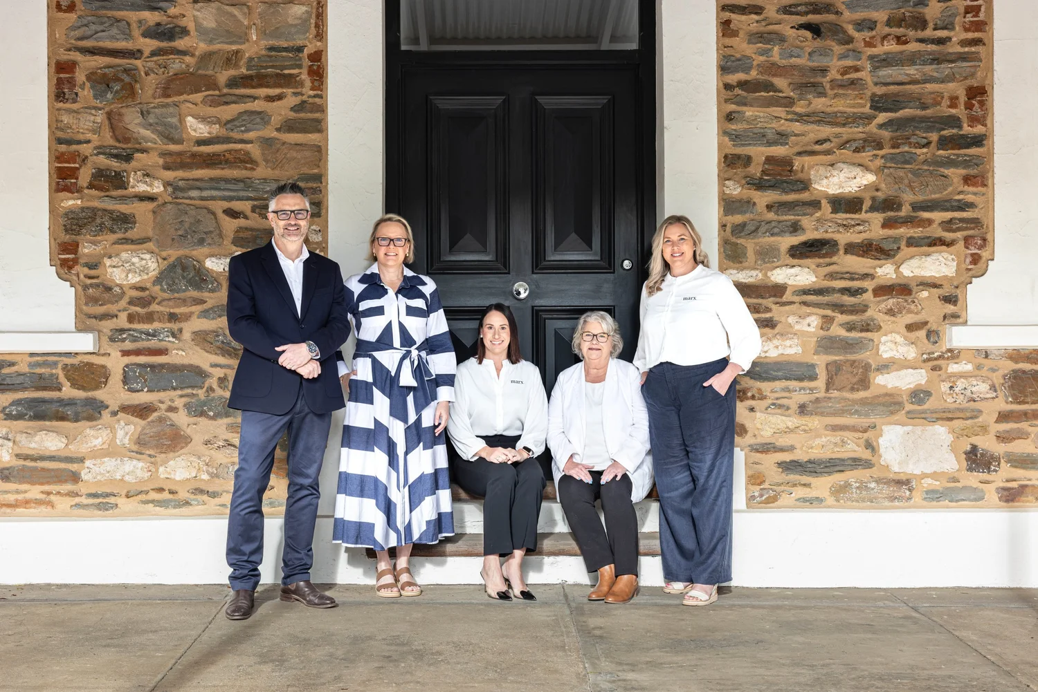 Small team portrait at a heritage door between stone walls