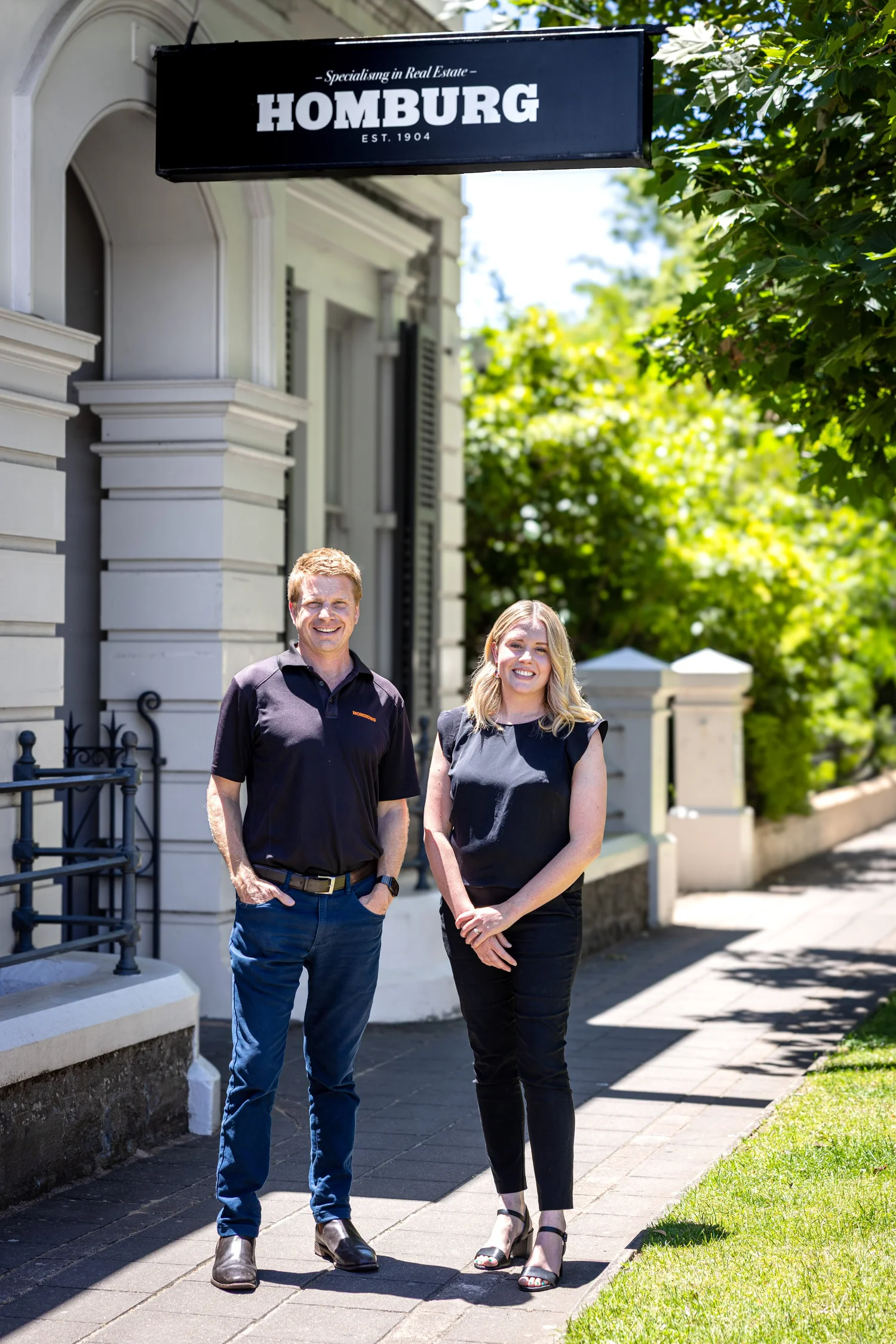 Two real estate agents under their office sign