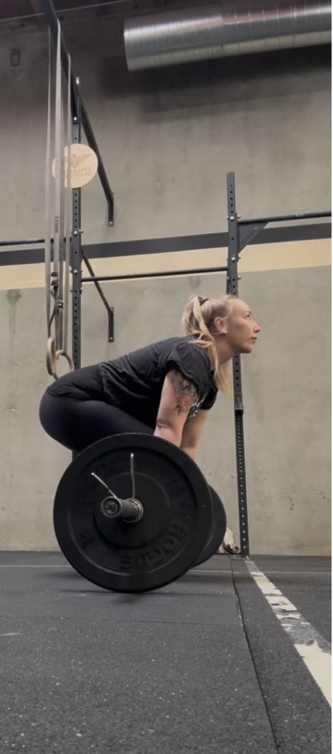 Woman lifting a barbell in a crossfit gym flashbang
