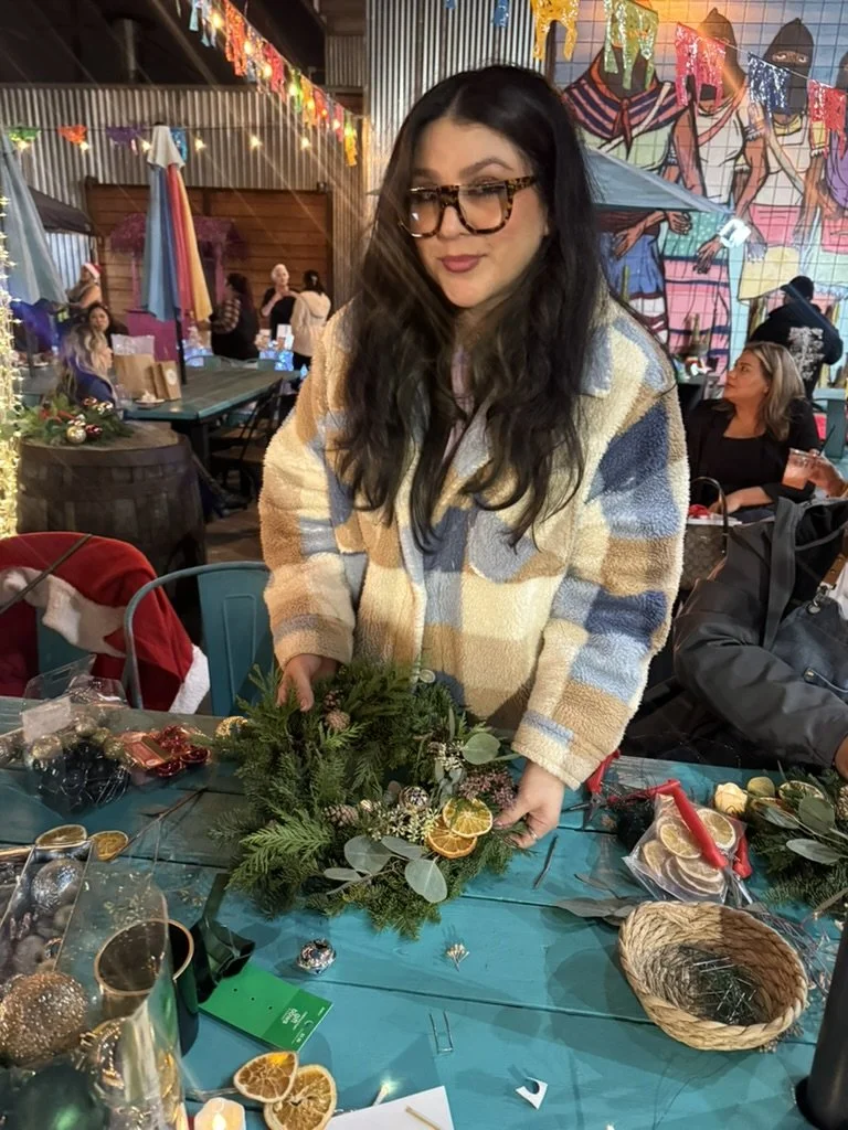 woman with glasses holding a holiday wreath