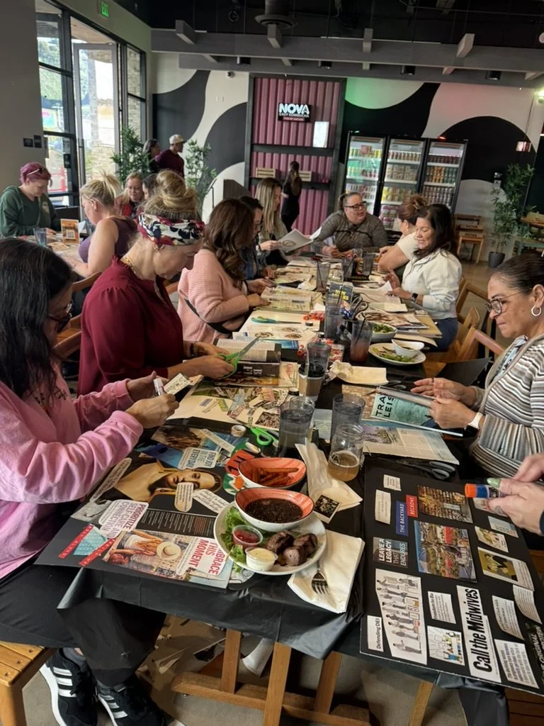 Women gathered around a table during a book club meeting at a restaurant or cafe, with food and drinks on the table.