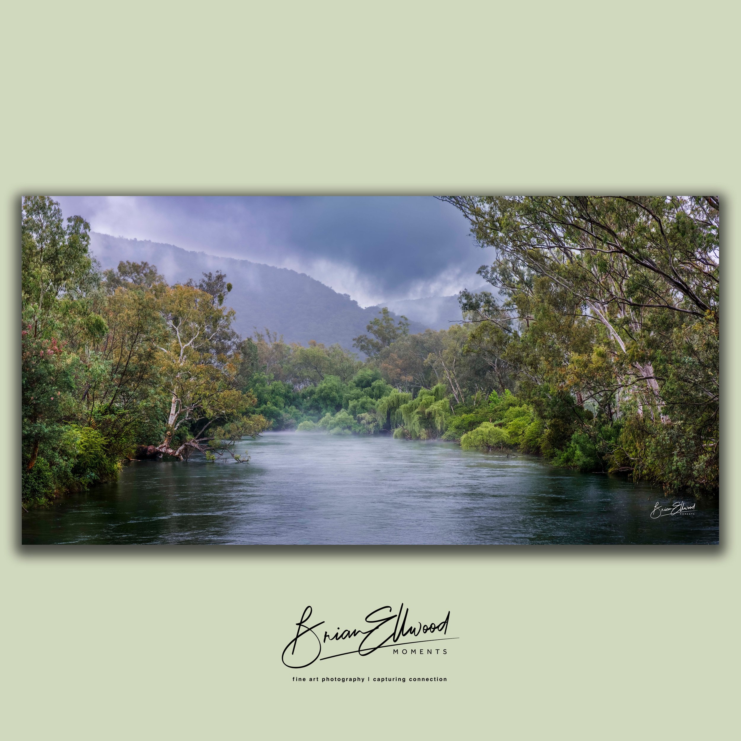 Three landscape photographs hanging on a green wall above a white table with ceramic vases and bowls.