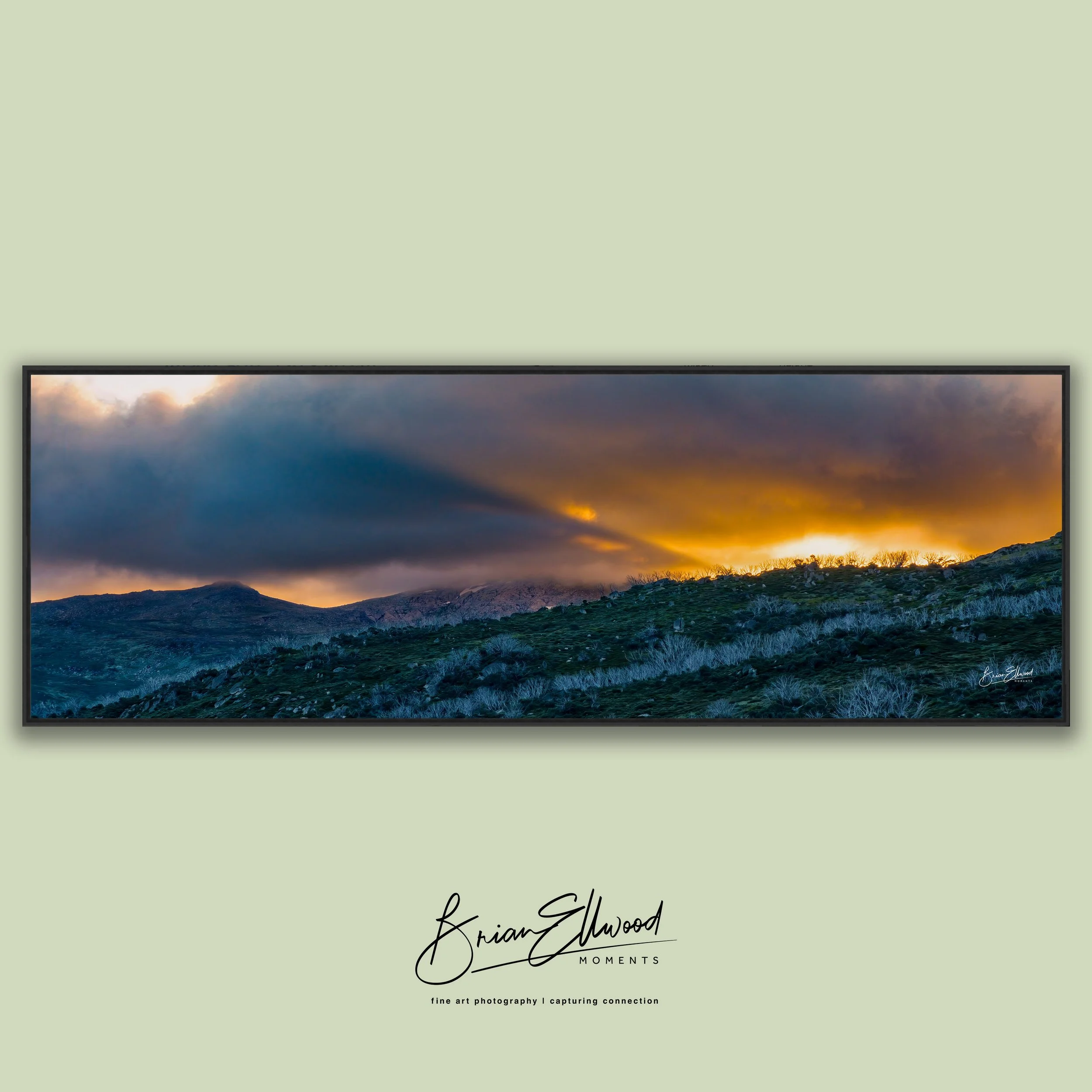 Three landscape photographs hanging on a green wall above a white table with ceramic vases and bowls.