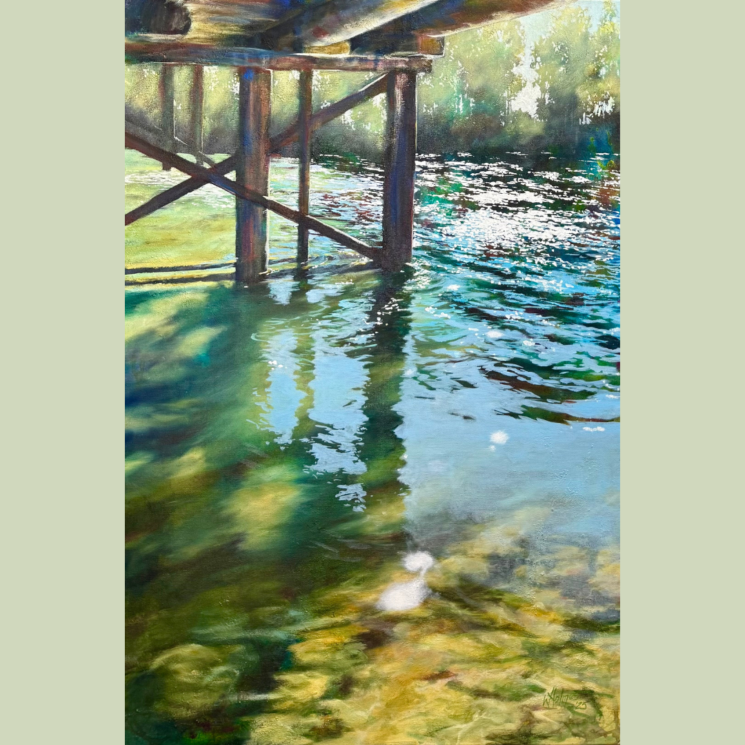 Water under a wooden bridge with reflections of the bridge and nearby trees on the water's surface.