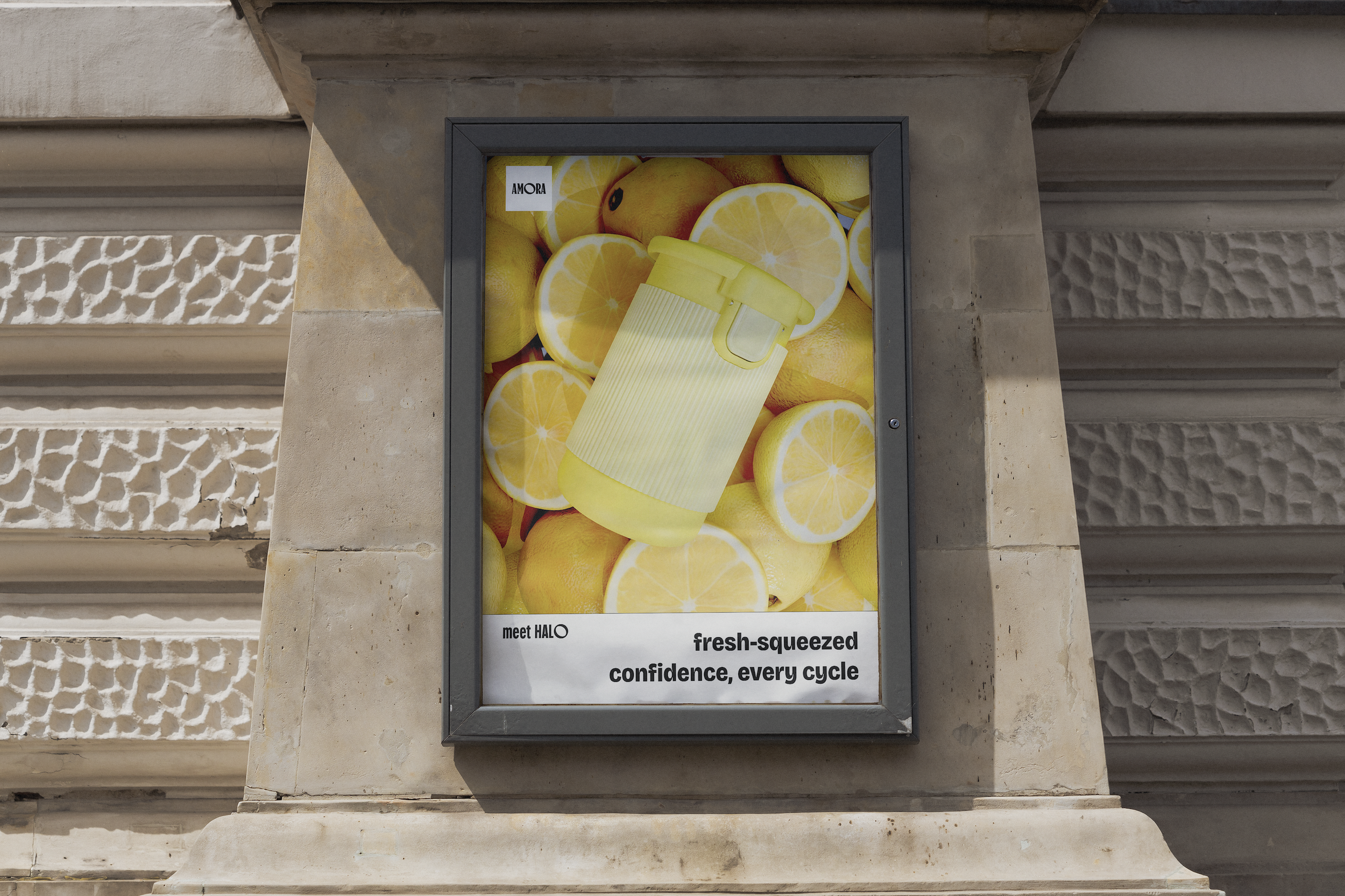 Outdoor poster featuring Halo in the Lemon Drop colourway displayed over sliced lemons, with the text “fresh-squeezed confidence, every cycle” and the brand labels “AMORA” and “meet HALO.”