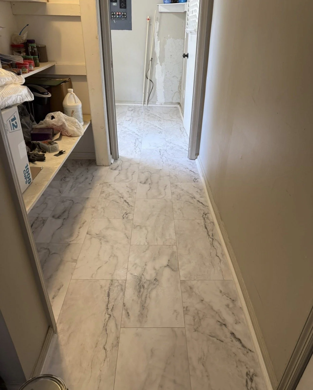 Marble tile floor in a hallway leading to a laundry room under construction.