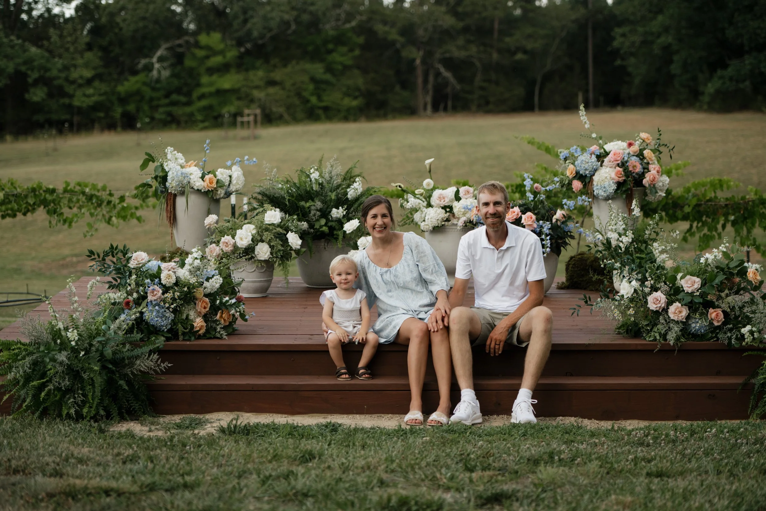 Beautiful outdoor wedding ceremony platform at wedding venue, surrounded by large floral arrangements in grassy field. Outside of Charlotte, North Carolina.