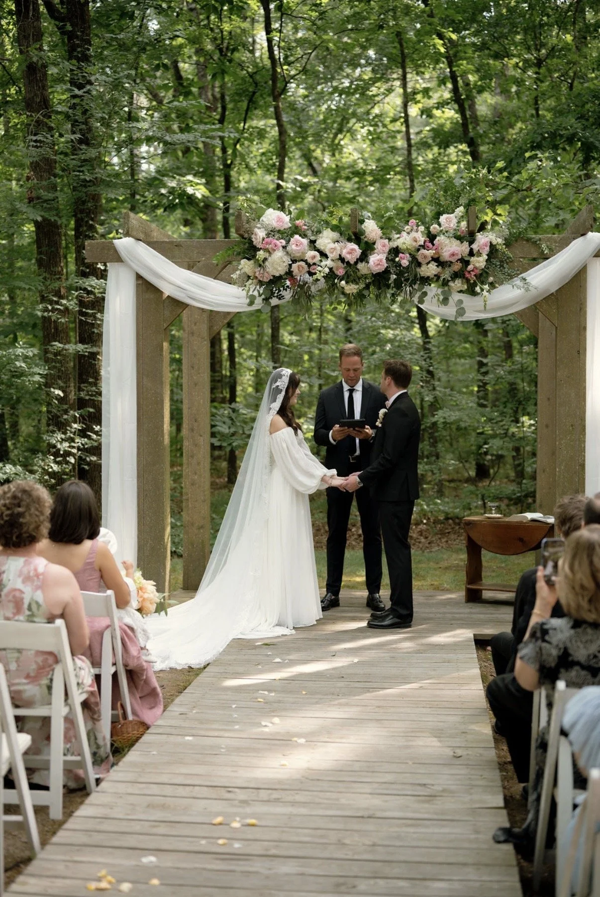 A bride and groom at outdoor wedding ceremony in a wooded area. Beautiful flower arrangement. Near Charlotte, NC.