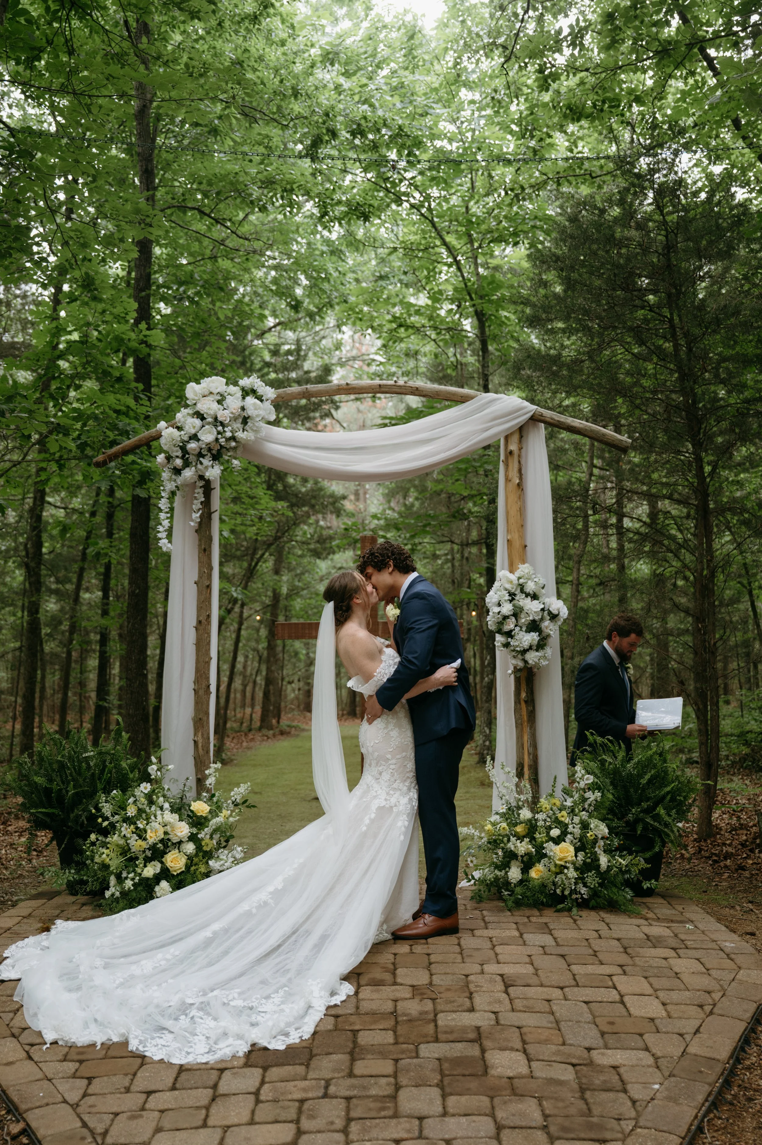 A bride and groom at outdoor wedding ceremony in a wooded area. Beautiful flower arrangement. Near Charlotte, NC.