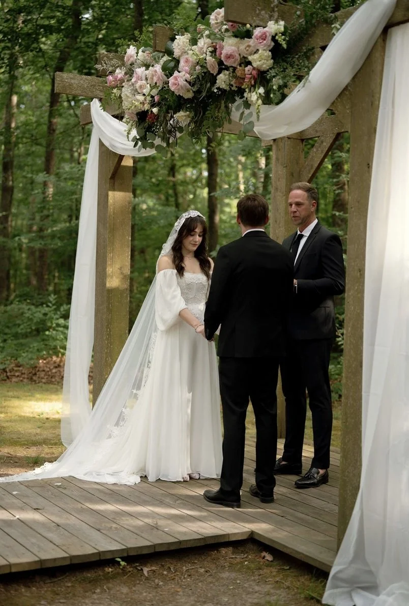 A bride and groom at outdoor wedding ceremony in a wooded area. Beautiful flower arrangement. Near Charlotte, NC.