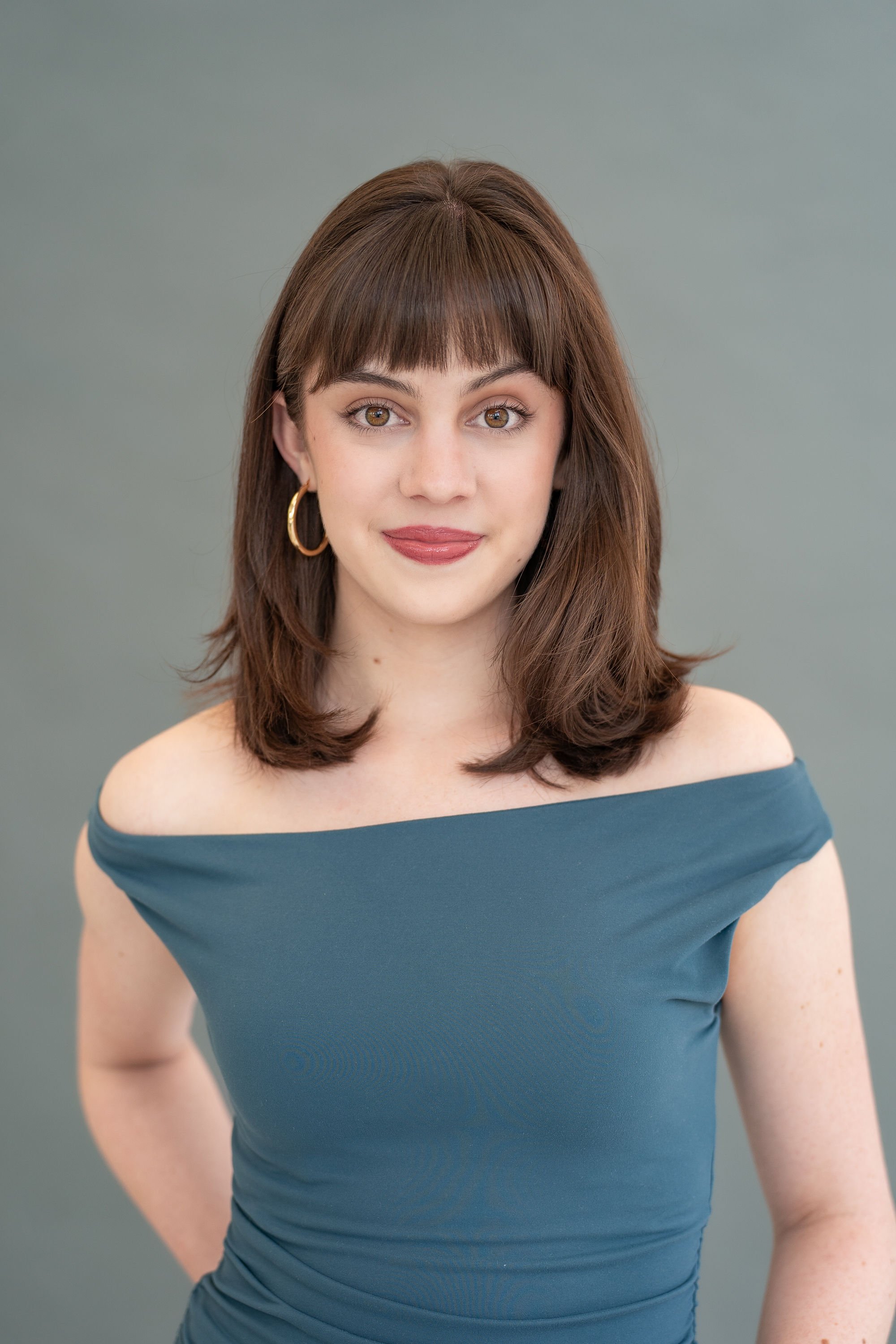 Gabriela Ayala Yarbrough smirking in a blue off-the shoulder top