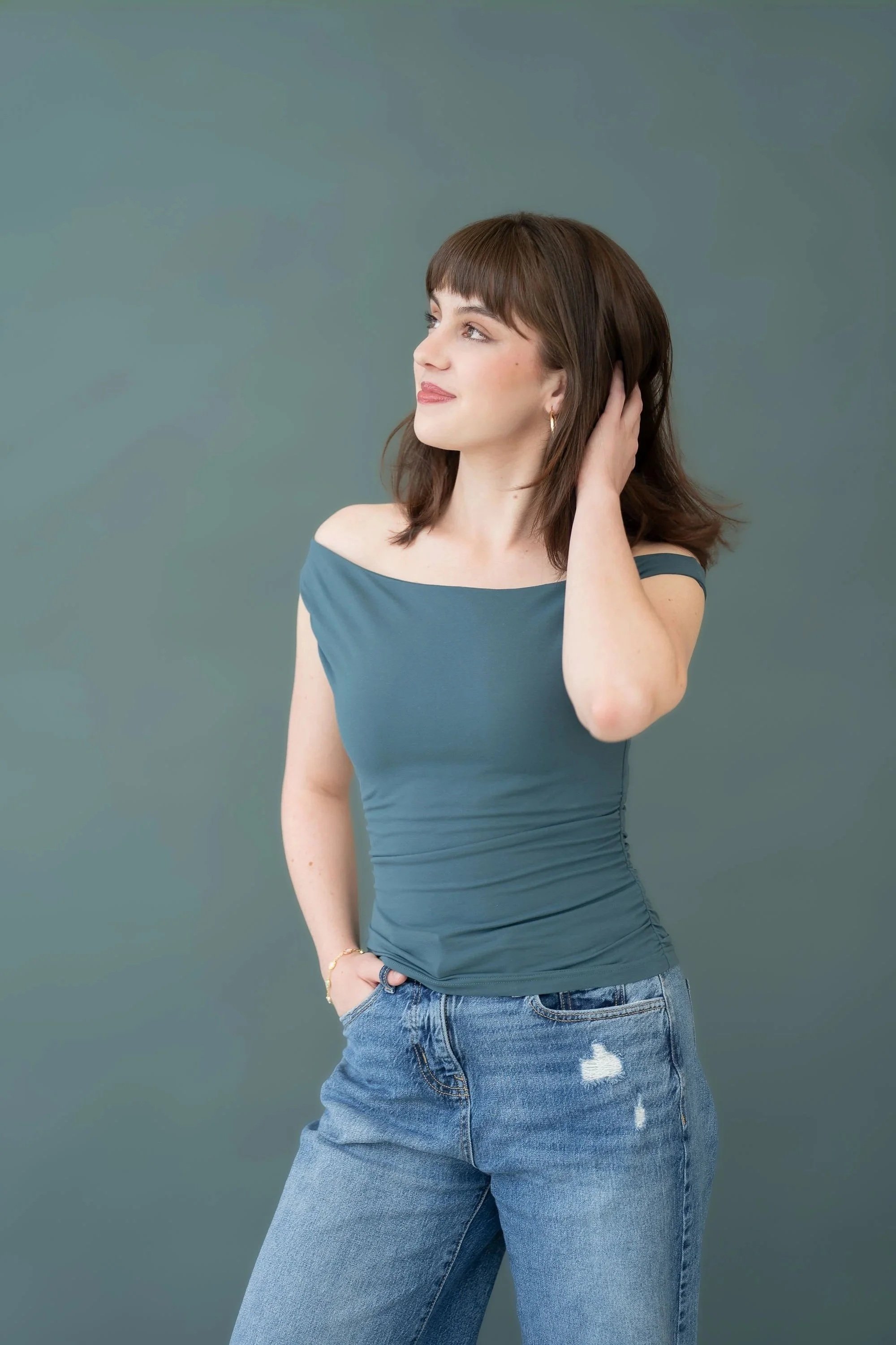 Gabriela Ayala Yarbrough turns to the left with a hand in her hair, three-quarter body shot