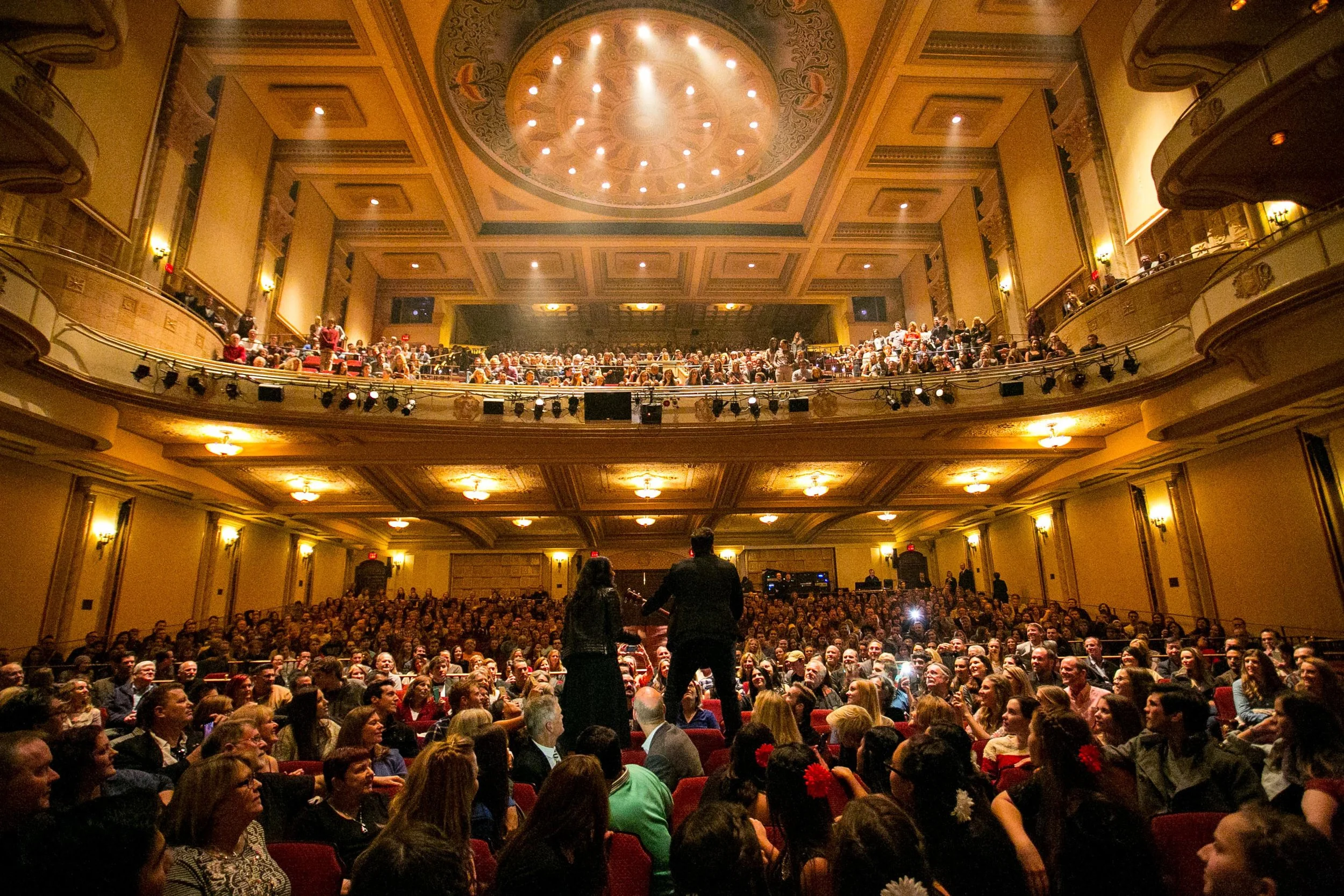Mountains with snow caps in the background and a grassy hillside with a modern building in the foreground.