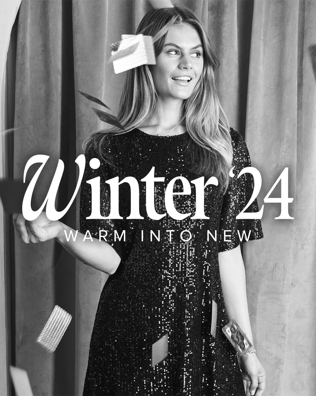 Black and white photo of a young woman in a sequined dress, standing in front of curtains, with falling confetti, and text overlay that reads 'Winter 24 Warm Into New'.